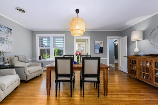 dining space featuring crown molding and light hardwood / wood-style floors