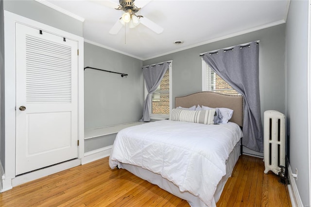 bedroom with ceiling fan, hardwood / wood-style floors, radiator heating unit, and ornamental molding