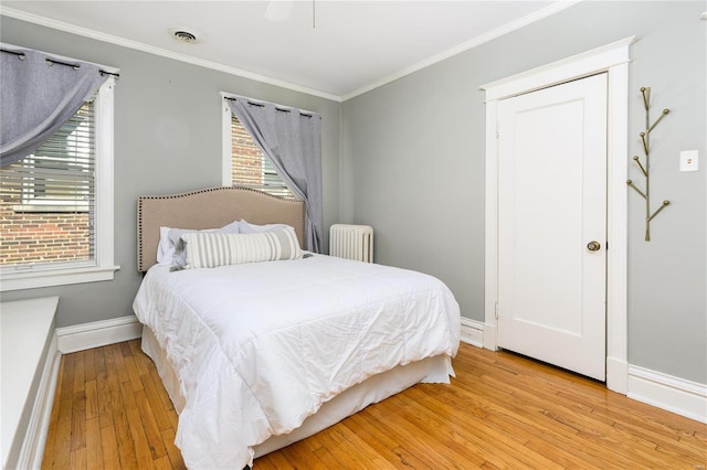 bedroom with ceiling fan, multiple windows, light hardwood / wood-style floors, and radiator heating unit