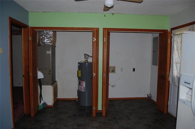 hallway with a textured ceiling, electric water heater, and dark tile floors