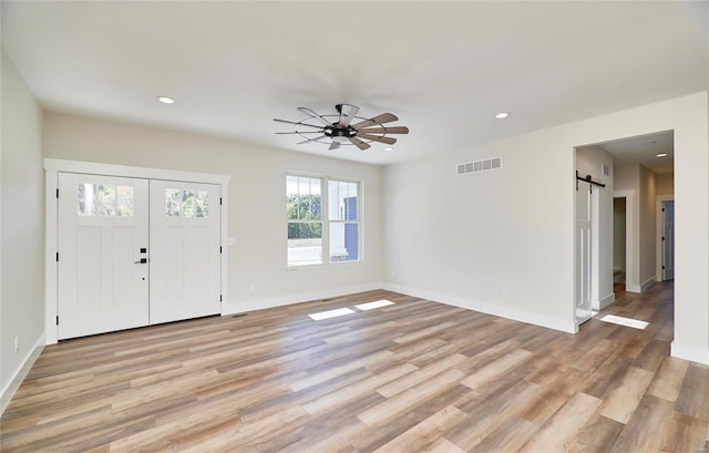 entrance foyer featuring light hardwood / wood-style flooring, a barn door, and ceiling fan