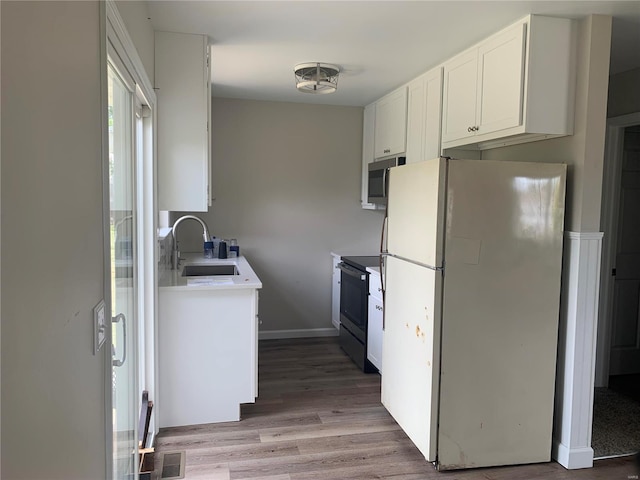 kitchen featuring white refrigerator, sink, black electric range, hardwood / wood-style flooring, and white cabinetry