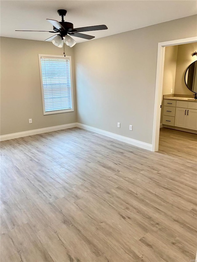 unfurnished bedroom featuring ceiling fan, ensuite bathroom, and light hardwood / wood-style floors