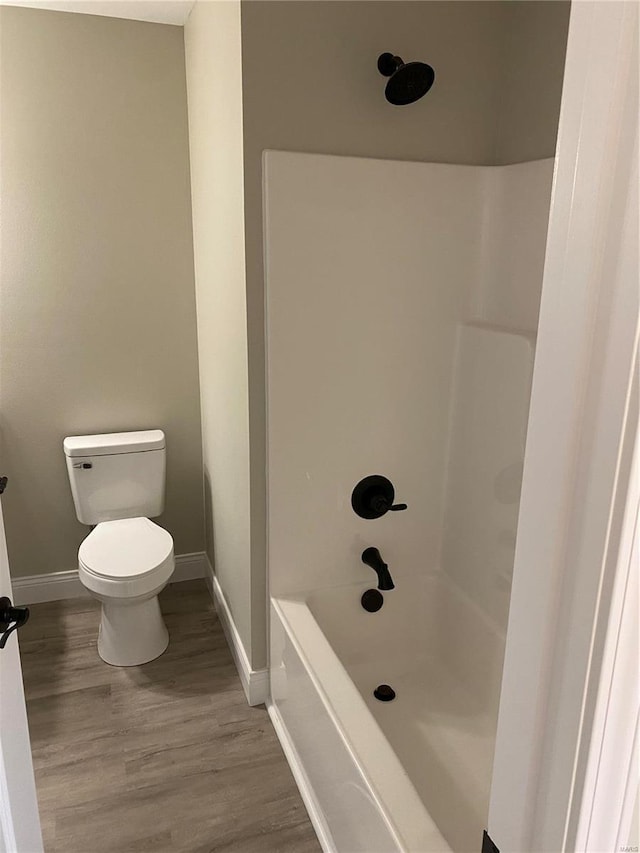 bathroom with hardwood / wood-style flooring, a shower, and toilet