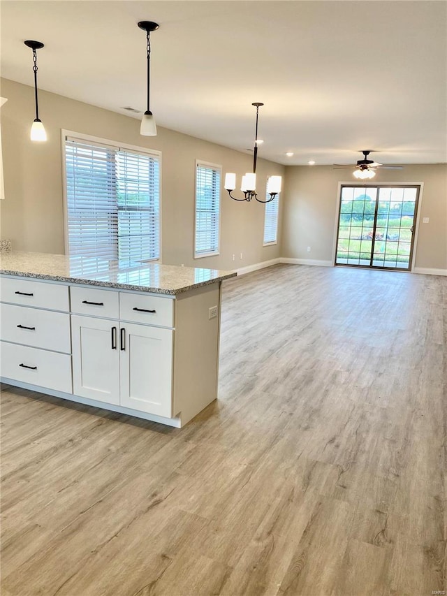 kitchen featuring white cabinetry, decorative light fixtures, light stone counters, and light hardwood / wood-style flooring