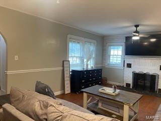 living room featuring ceiling fan, dark hardwood / wood-style floors, and a fireplace