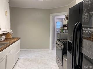 kitchen featuring stainless steel stove, black fridge, white cabinets, and light tile floors