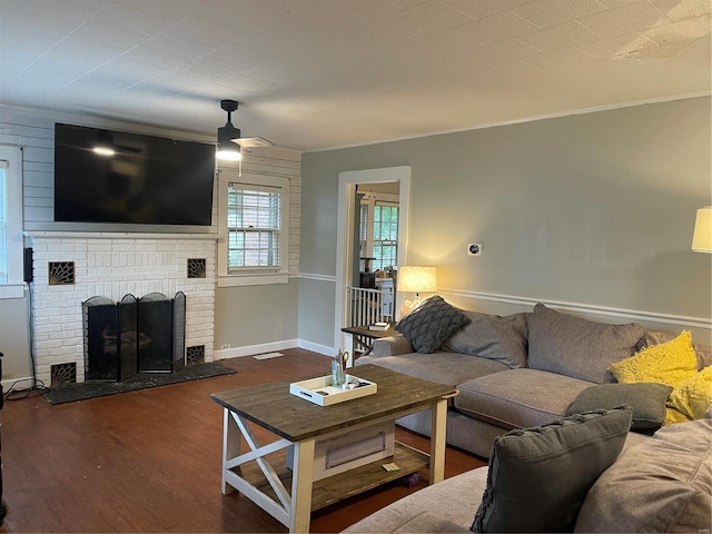 living room with ceiling fan, ornamental molding, a fireplace, and dark wood-type flooring