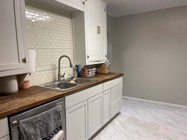 kitchen featuring stainless steel dishwasher, wooden counters, backsplash, sink, and white cabinetry