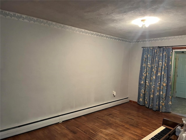 unfurnished room featuring a textured ceiling, dark hardwood / wood-style floors, and a baseboard heating unit