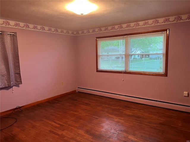 empty room featuring hardwood / wood-style flooring, a healthy amount of sunlight, a textured ceiling, and a baseboard radiator