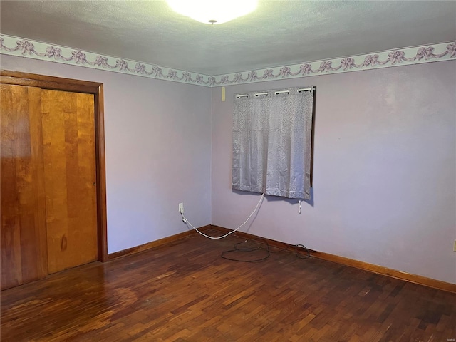 unfurnished room with a textured ceiling and dark hardwood / wood-style flooring