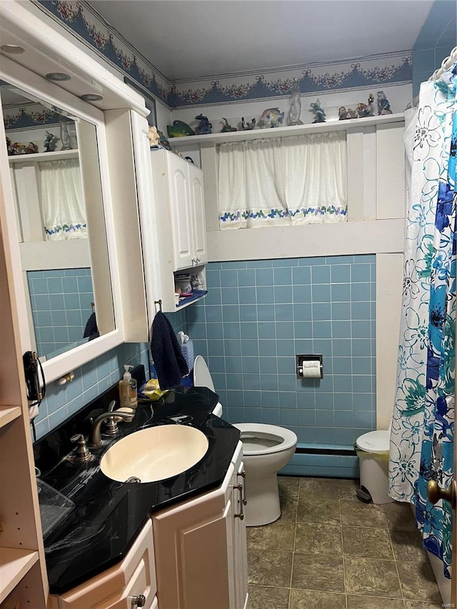 bathroom featuring toilet, vanity, tile walls, and a baseboard heating unit