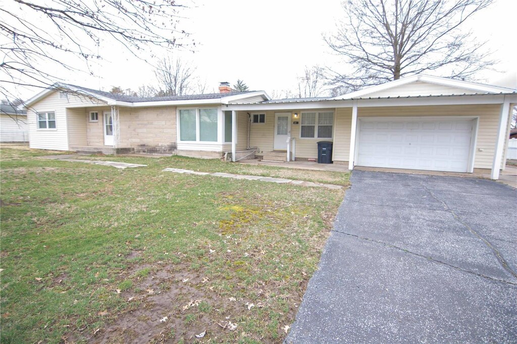 ranch-style home with a front yard, driveway, a chimney, entry steps, and a garage