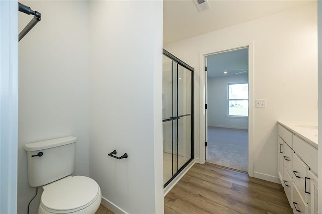 bathroom featuring vanity, hardwood / wood-style flooring, toilet, and a shower with shower door