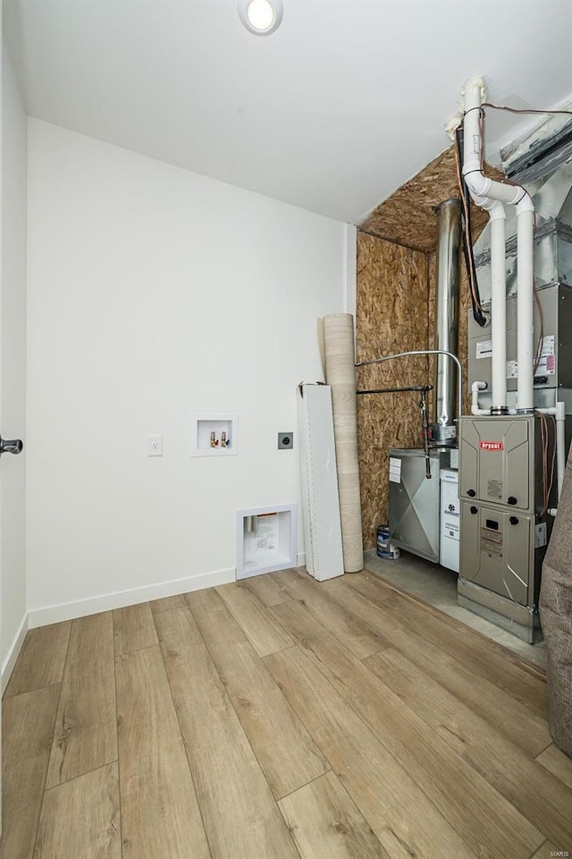 washroom featuring electric dryer hookup, hookup for a washing machine, light hardwood / wood-style flooring, and heating unit