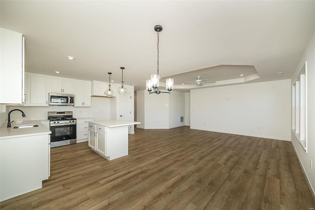 kitchen with sink, dark hardwood / wood-style floors, a kitchen island, white cabinetry, and stainless steel appliances