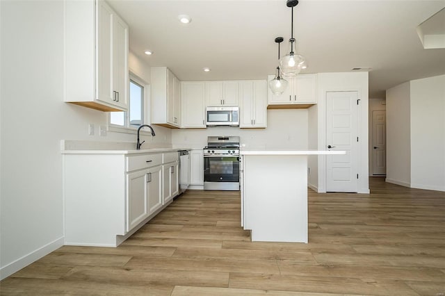 kitchen with appliances with stainless steel finishes, a center island, light hardwood / wood-style flooring, and white cabinetry