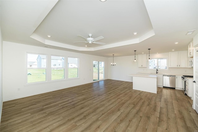 unfurnished living room featuring plenty of natural light, dark wood-type flooring, and a tray ceiling