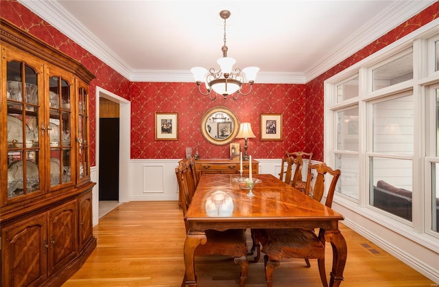 dining room featuring light hardwood / wood-style floors, crown molding, and a notable chandelier