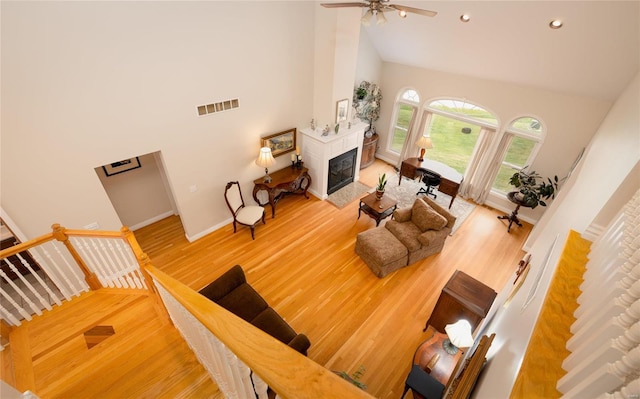 living room with ceiling fan, a high ceiling, and hardwood / wood-style flooring