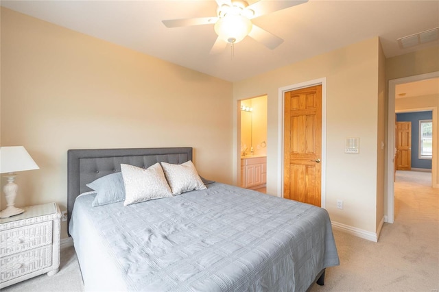 bedroom featuring ceiling fan, light colored carpet, and ensuite bathroom