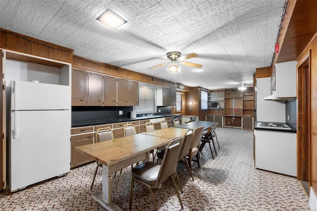 kitchen featuring white refrigerator, stainless steel gas cooktop, ceiling fan, light colored carpet, and sink