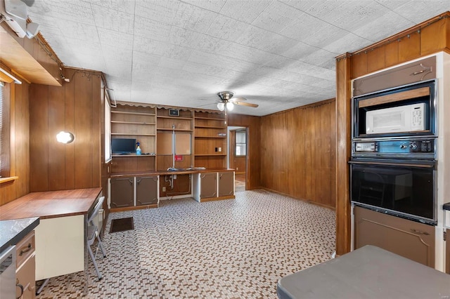 kitchen with white microwave, wood walls, oven, ceiling fan, and light tile floors