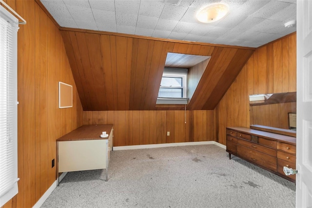 additional living space featuring vaulted ceiling, wood walls, and light colored carpet