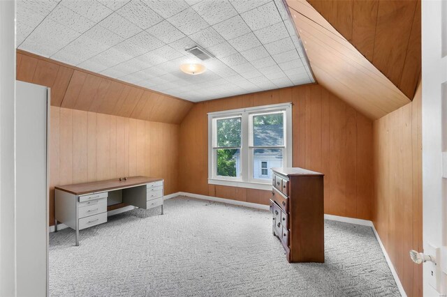 bonus room with lofted ceiling, wood walls, and light carpet