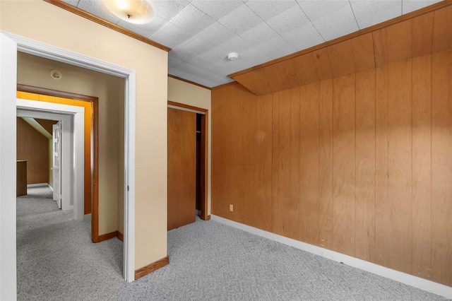 unfurnished bedroom with crown molding, carpet flooring, and wood walls