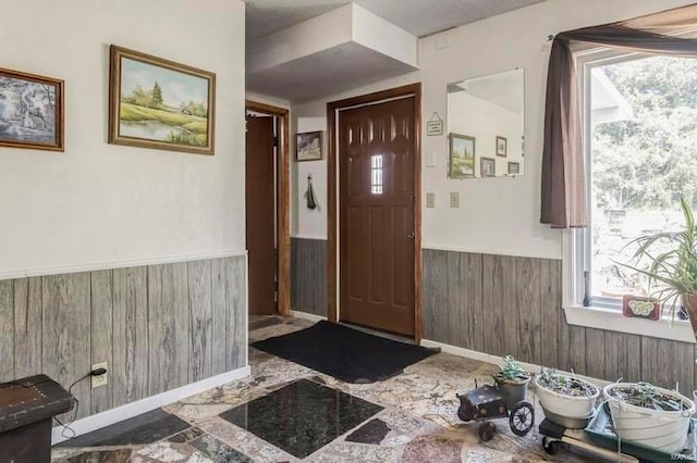 foyer entrance with wood walls and tile flooring