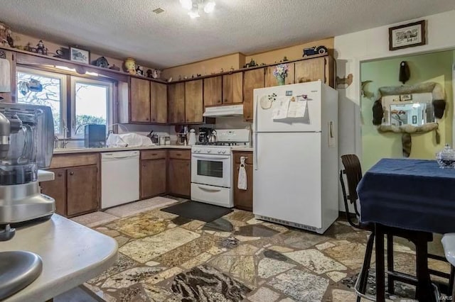 kitchen featuring white appliances, a textured ceiling, and light tile floors