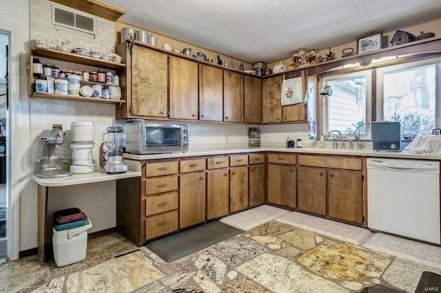 kitchen with white dishwasher, sink, a textured ceiling, and light tile floors