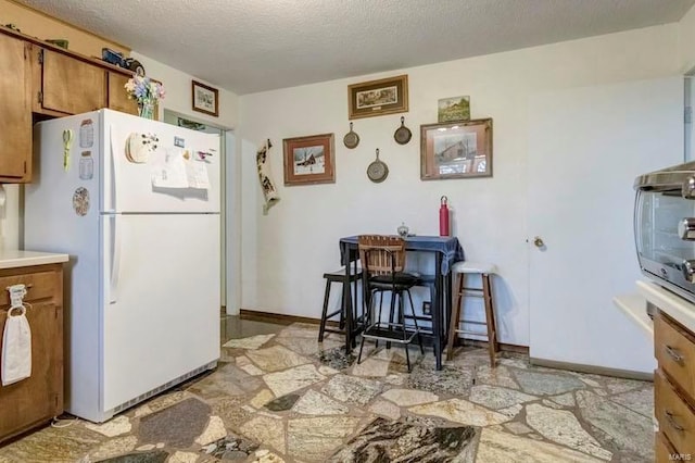 kitchen featuring a textured ceiling and white fridge