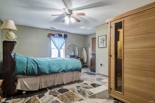 tiled bedroom with ceiling fan and a textured ceiling