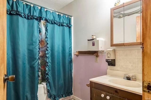 bathroom with a textured ceiling and vanity with extensive cabinet space