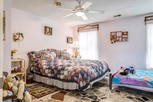 bedroom featuring tile flooring, ceiling fan, and a textured ceiling