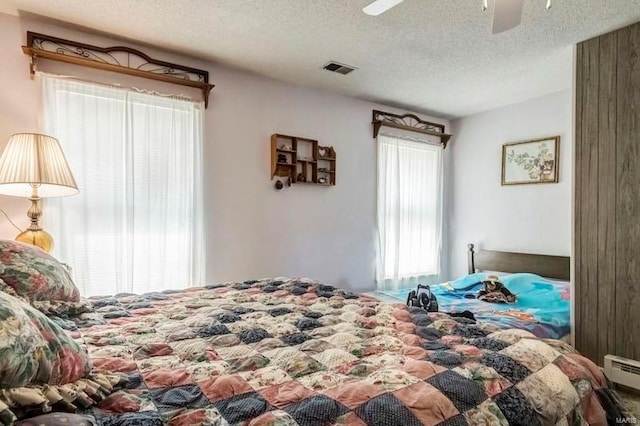 bedroom featuring ceiling fan, a textured ceiling, and a baseboard radiator