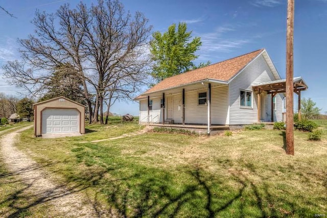 view of front facade with a garage, a front lawn, covered porch, and an outdoor structure