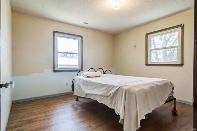 bedroom featuring a textured ceiling, wood-type flooring, and multiple windows