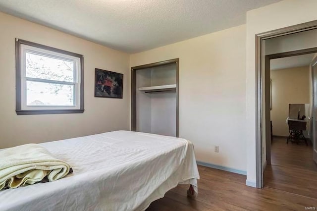 bedroom featuring a closet, a textured ceiling, and dark wood-type flooring