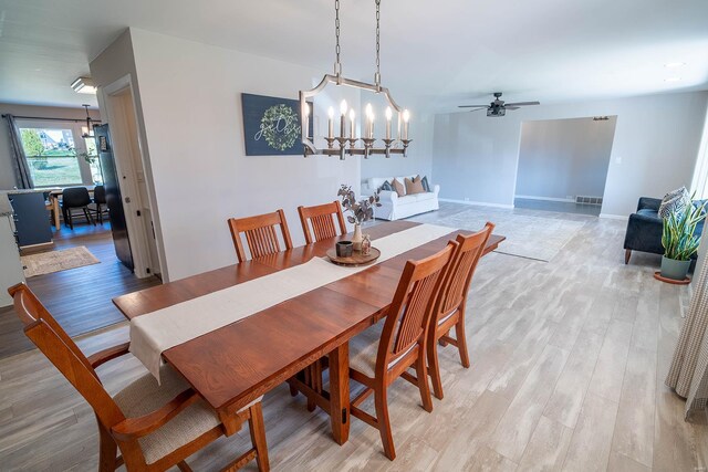 dining room featuring ceiling fan with notable chandelier and light hardwood / wood-style floors