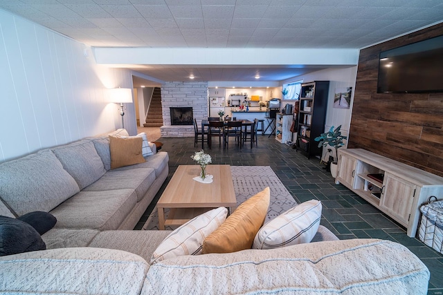 living room with a stone fireplace and wooden walls