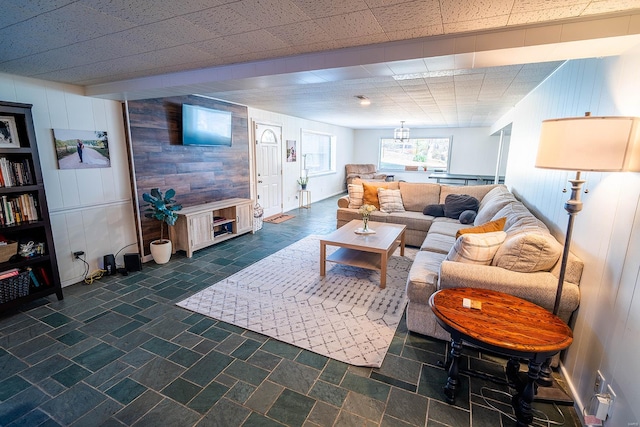 living room featuring a paneled ceiling and wooden walls