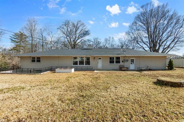 rear view of property featuring a yard, a jacuzzi, and a patio area