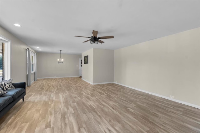 unfurnished living room with ceiling fan with notable chandelier and light wood-type flooring