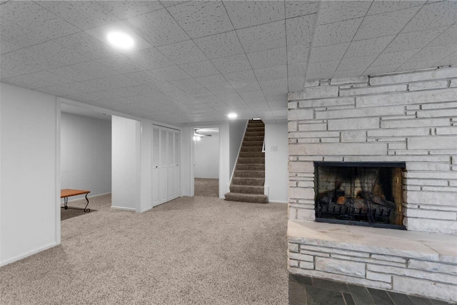 basement featuring a stone fireplace and carpet flooring