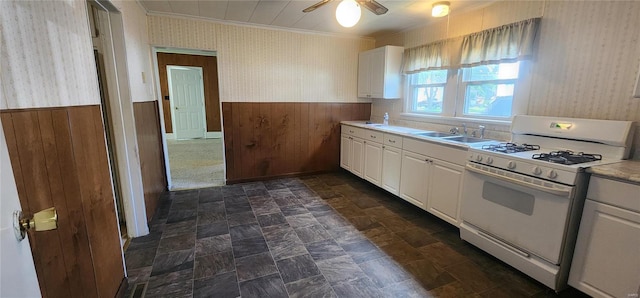 kitchen with ceiling fan, gas range gas stove, sink, white cabinets, and dark tile floors