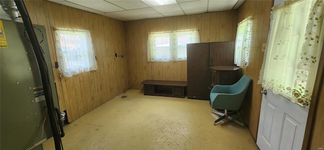 interior space featuring plenty of natural light, wooden walls, and a drop ceiling